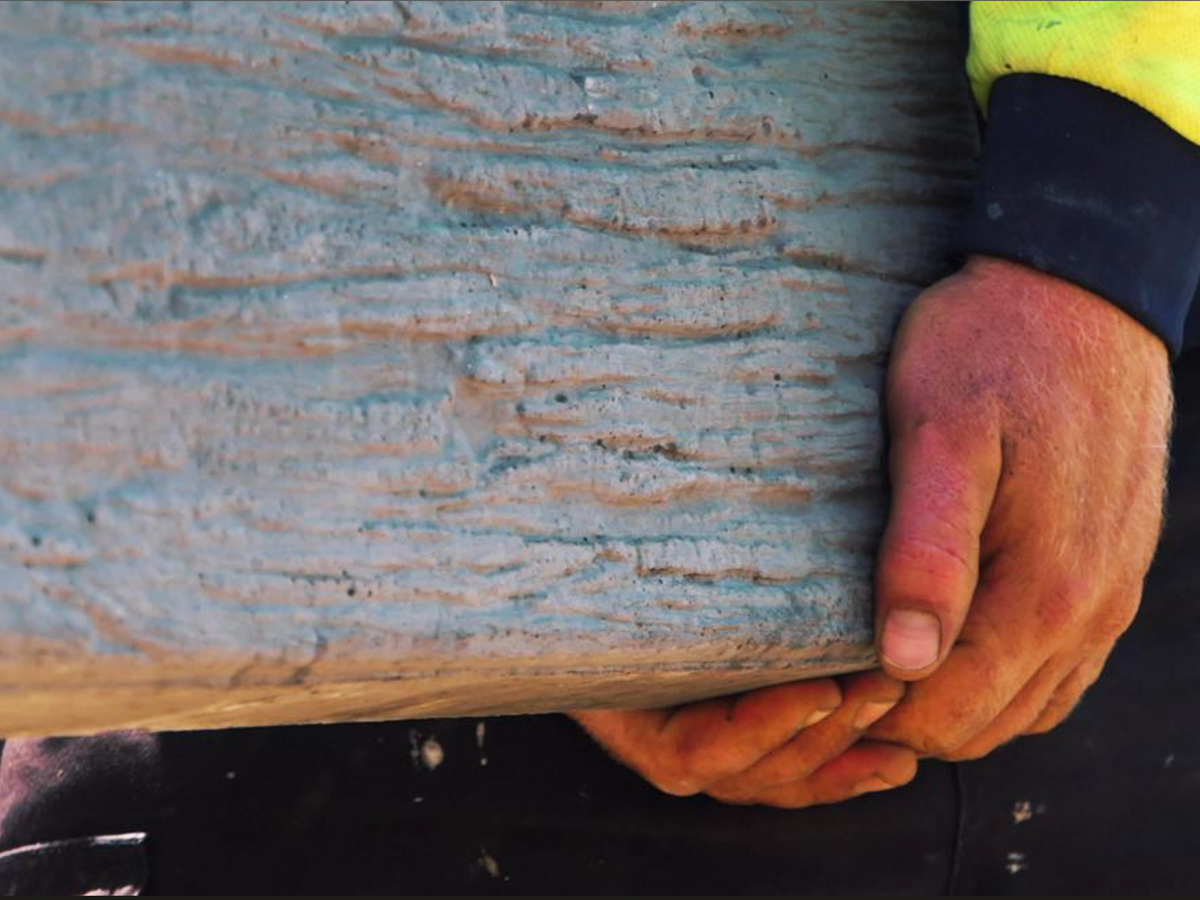 Landscaper carrying concrete sleeper to build retaining wall